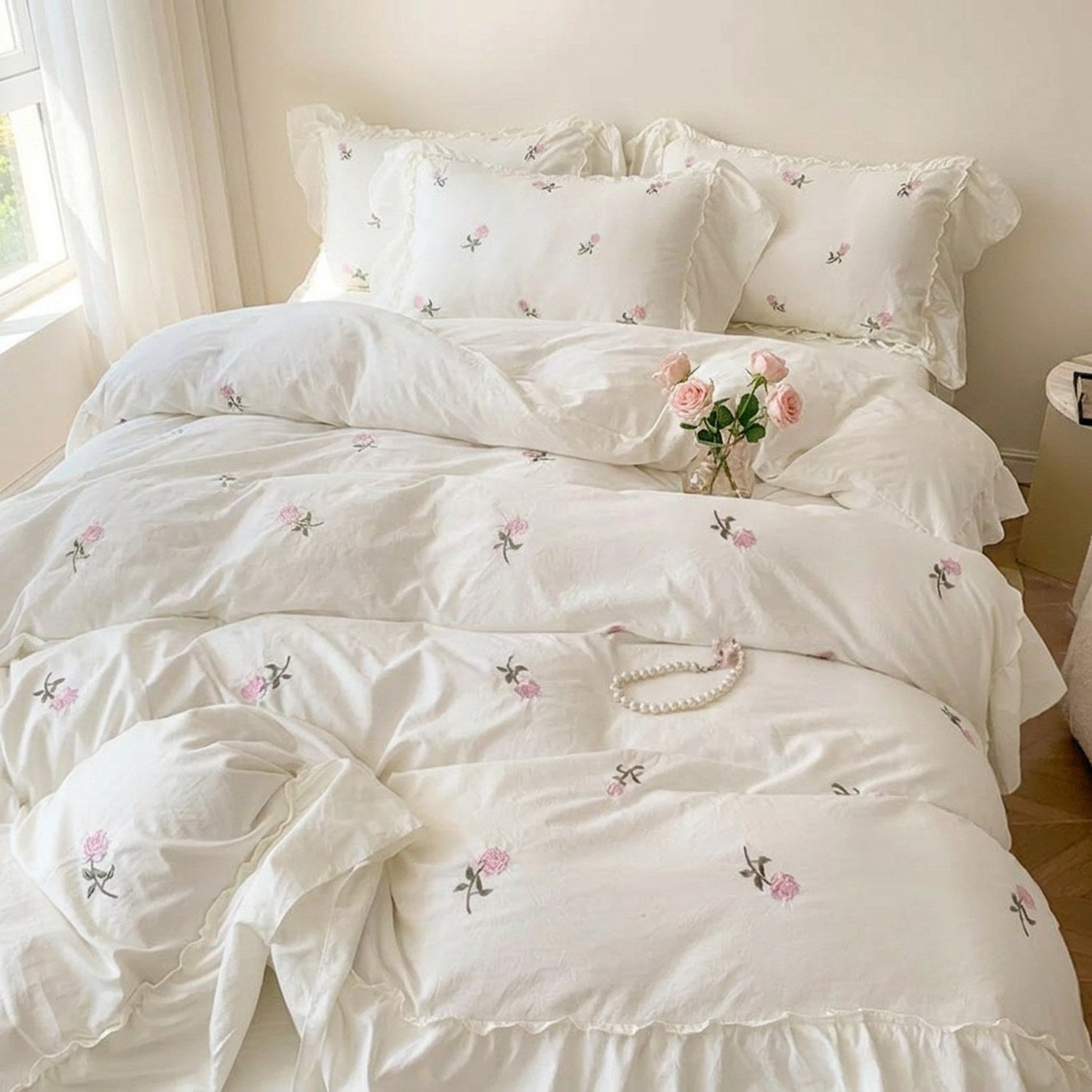 Parure de lit brodée de roses vue d'ensemble dans une chambre lumineuse avec fenêtre
