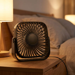 Ventilateur de bureau posé sur une table de chevet dans une chambre avec veilleuse allumée