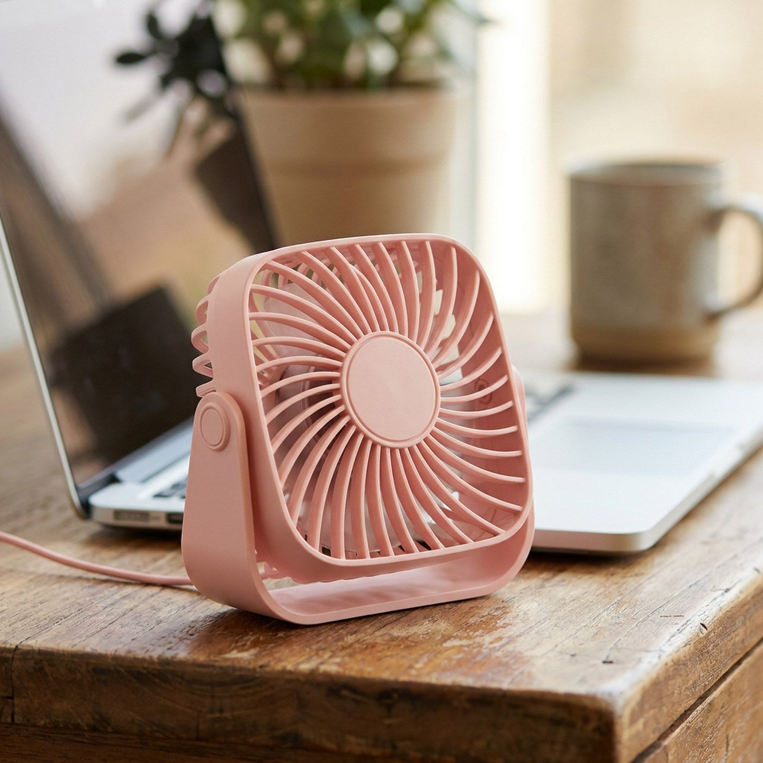 Ventilateur de bureau USB rose posé sur un bureau