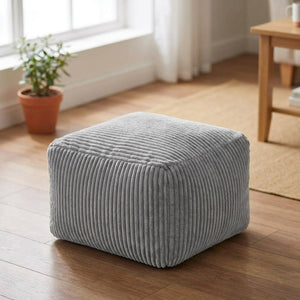 Tabouret pouf gris en velours côtelé posé au sol