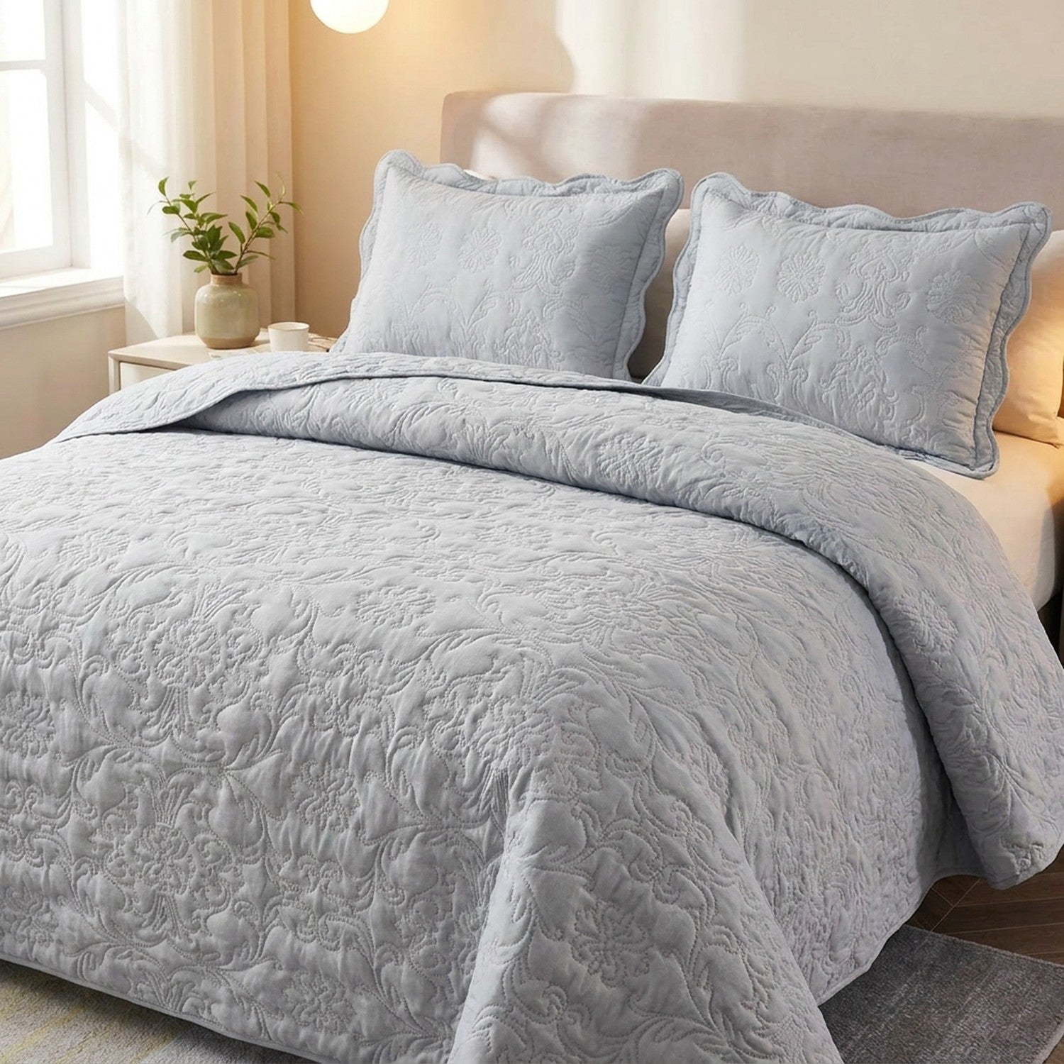Couvre-lit matelasse gris au motif damasse sur un lit avec deux taies assorties