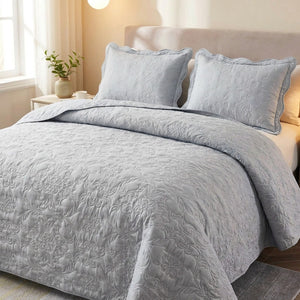 Couvre-lit matelasse gris au motif damasse sur un lit avec deux taies assorties