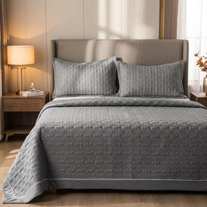 Couvre-lit matelassé gris avec deux taies assorties sur un lit