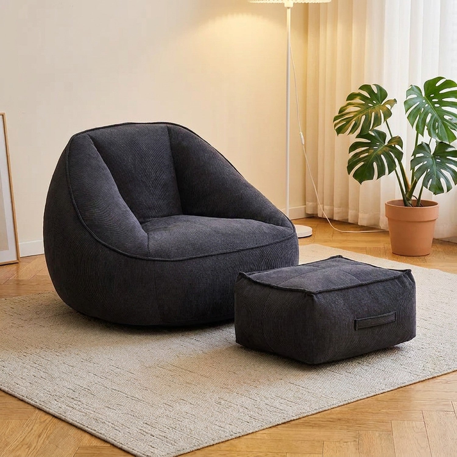 Fauteuil pouf en velours côtelé gris foncé avec repose-pieds dans un salon moderne