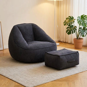 Fauteuil pouf en velours côtelé gris foncé avec repose-pieds dans un salon moderne