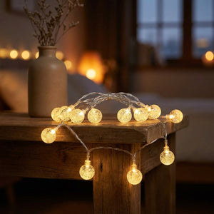 Guirlande lumineuse boule à bulles LED dorée posée sur une table en bois près d un vase et d une cheminée