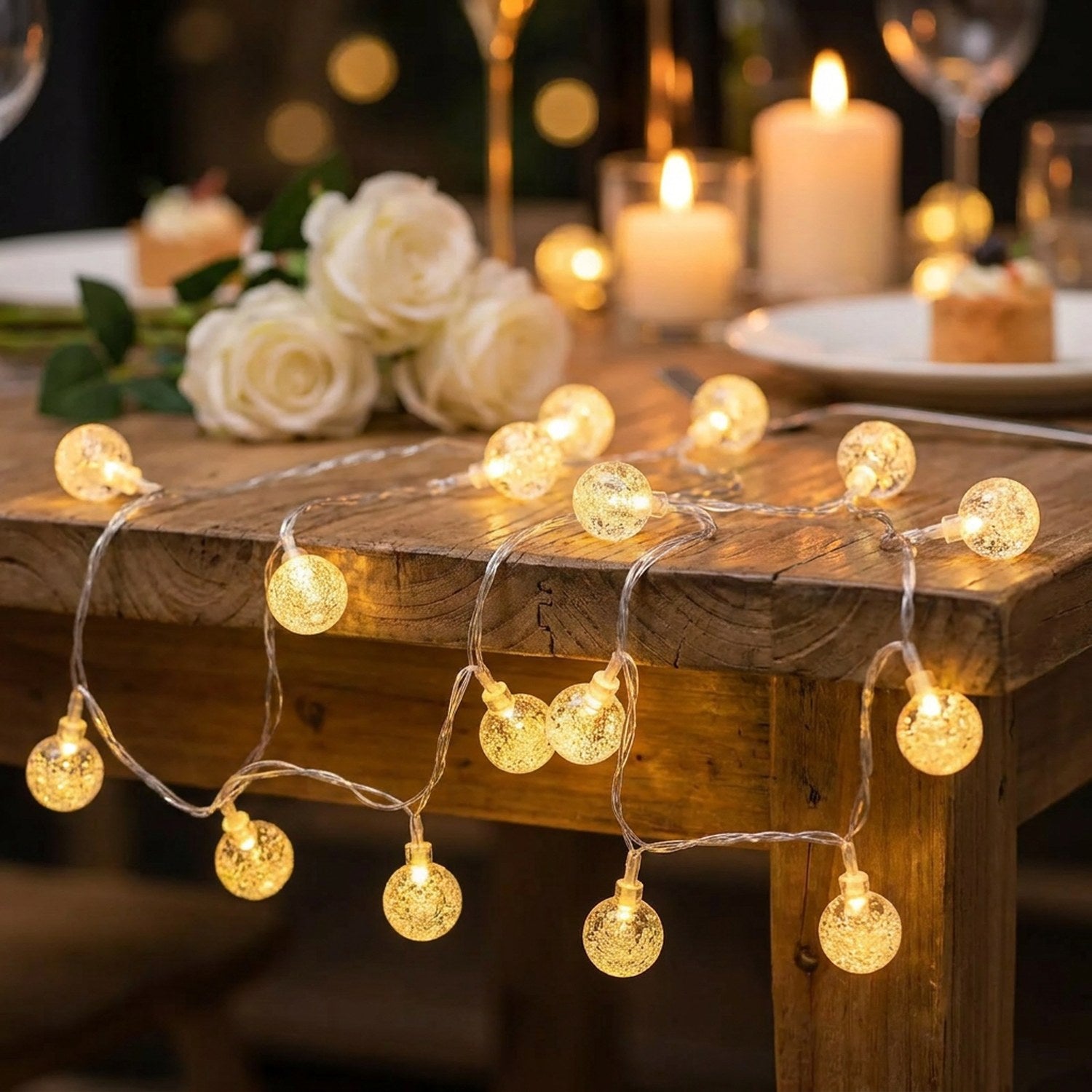 Guirlande lumineuse boule à bulles LED sur une table de mariage décorée de roses blanches et bougies