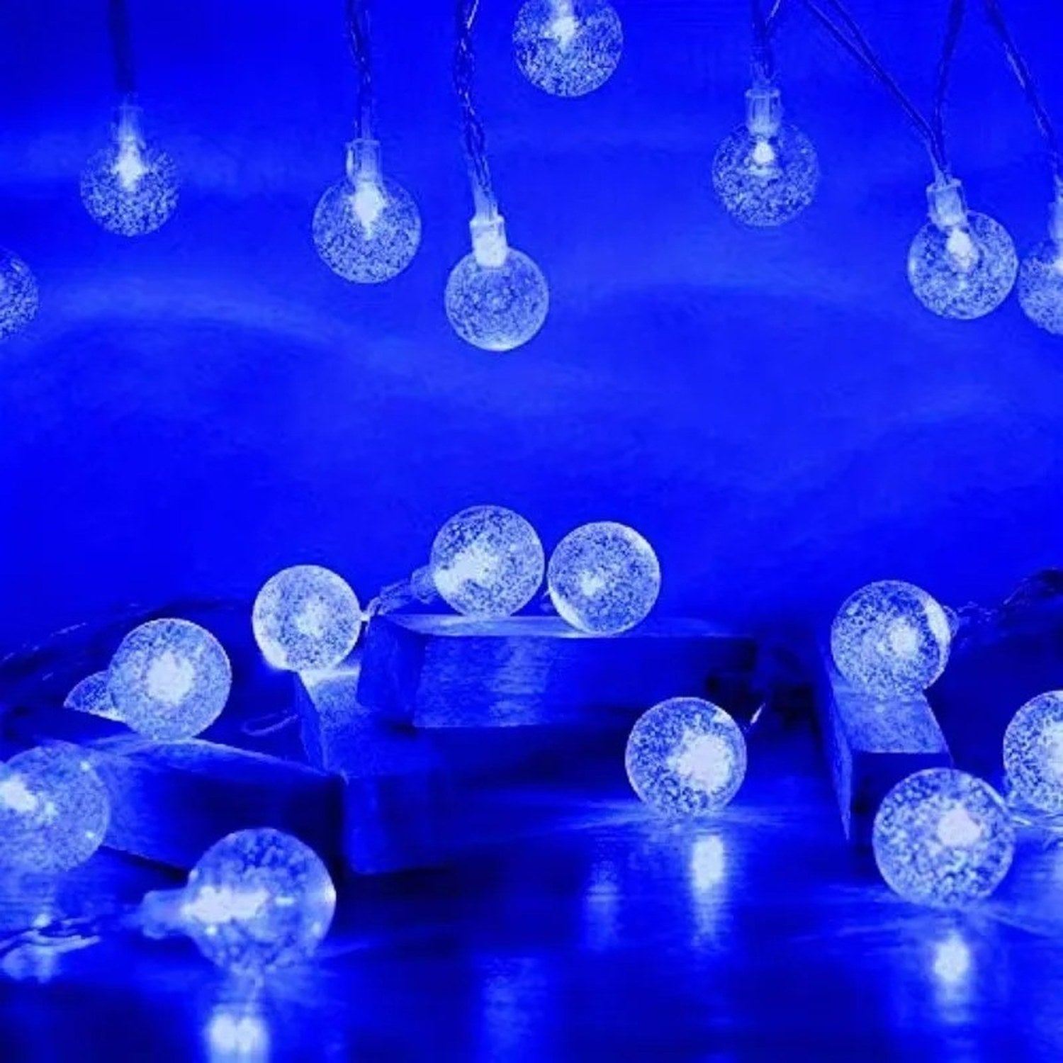 Guirlande lumineuse boule à bulles LED en variante bleue posée sur des blocs de bois