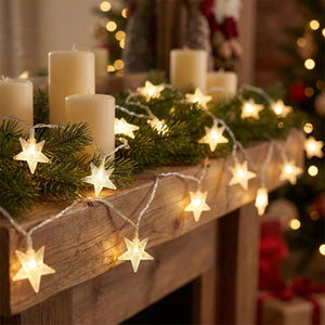 Guirlande d'étoiles LED posée sur une cheminée avec branches de pin et bougies