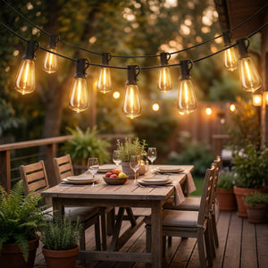 Guirlande guinguette solaire aux ampoules vintage allumées au-dessus d'une terrasse en bois le soir