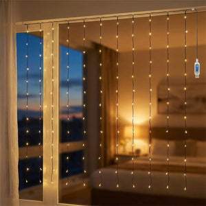 Guirlande lumineuse LED blanche chaude en rideau suspendue devant une fenêtre le soir