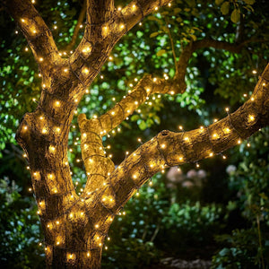 Guirlande LED solaire blanc chaud enroulée autour d'un arbre de jardin au crépuscule