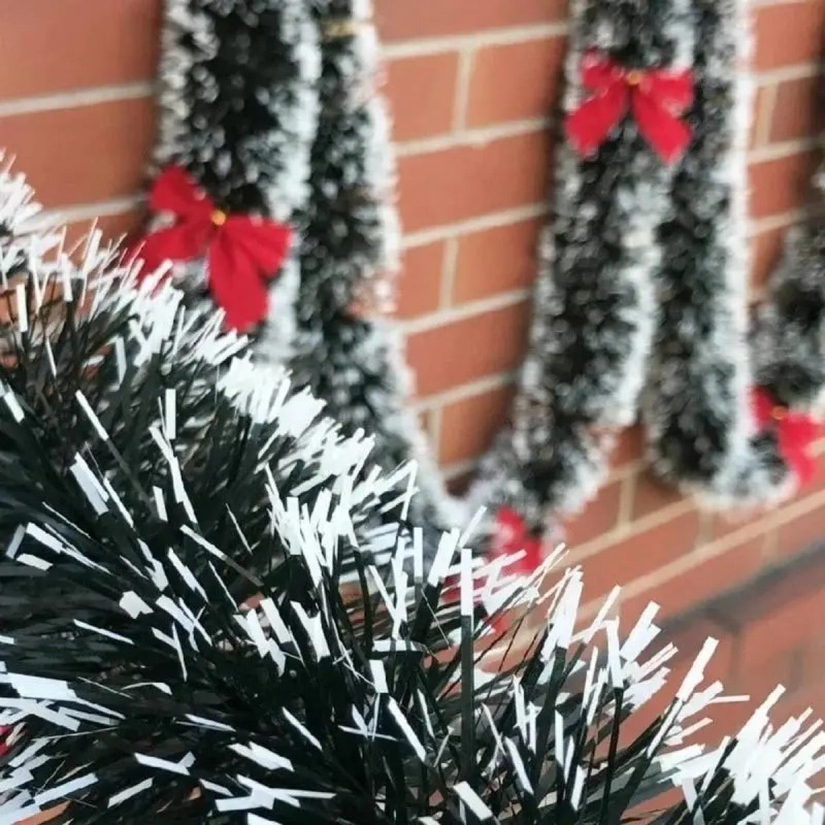 Guirlande de Noël verte avec petits nœuds rouges sur mur en briques