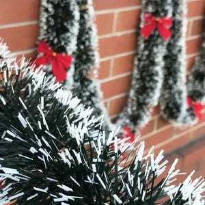 Guirlande de Noël verte avec petits nœuds rouges sur mur en briques