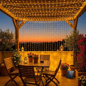 Guirlande rideau LED solaire sur une pergola méditerranéenne au coucher du soleil avec mobilier de jardin