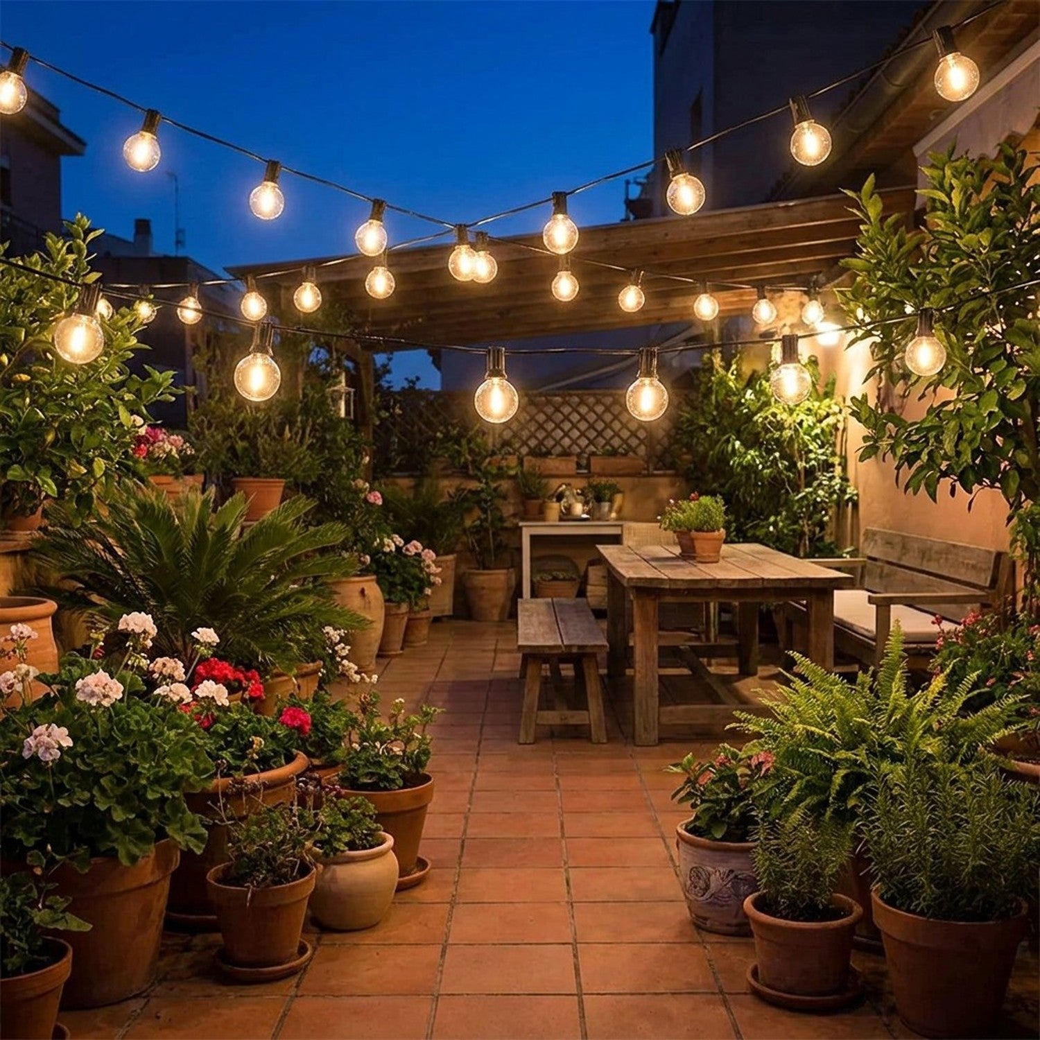 Guirlande guinguette G40 dans patio méditerranéen avec plantes en pots terracotta et table bois