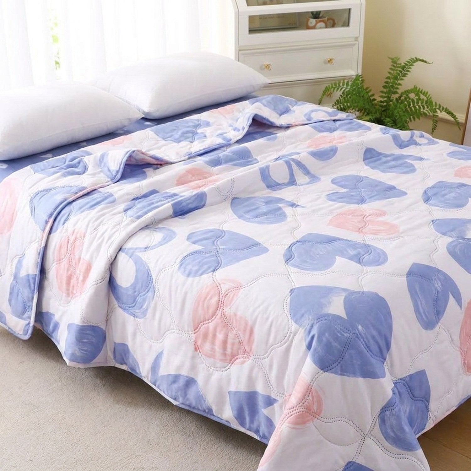 Couvre-lit d'été blanc à cœurs bleus et roses sur un lit dans une chambre douce