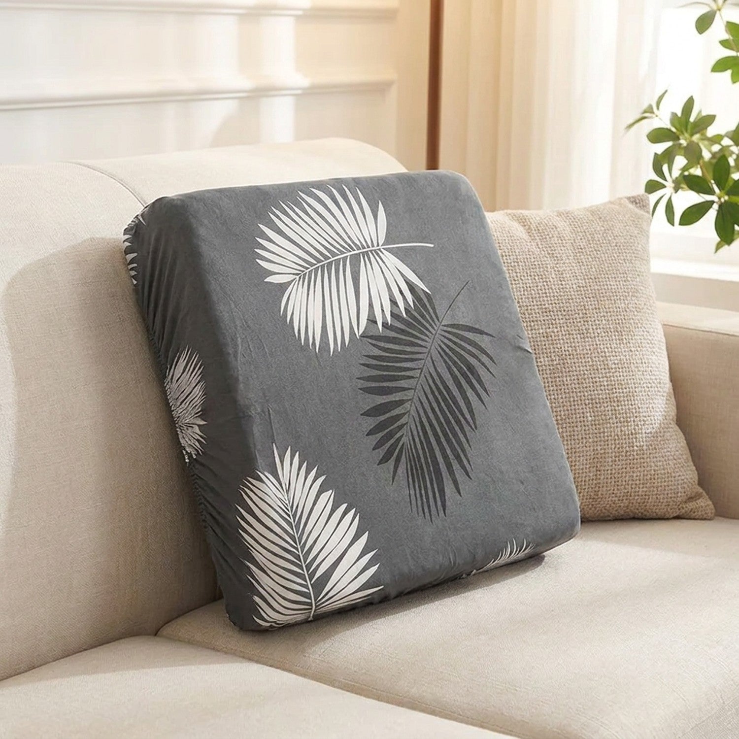 Housse de coussin de canapé extensible à motif feuillage gris posée sur une assise de salon