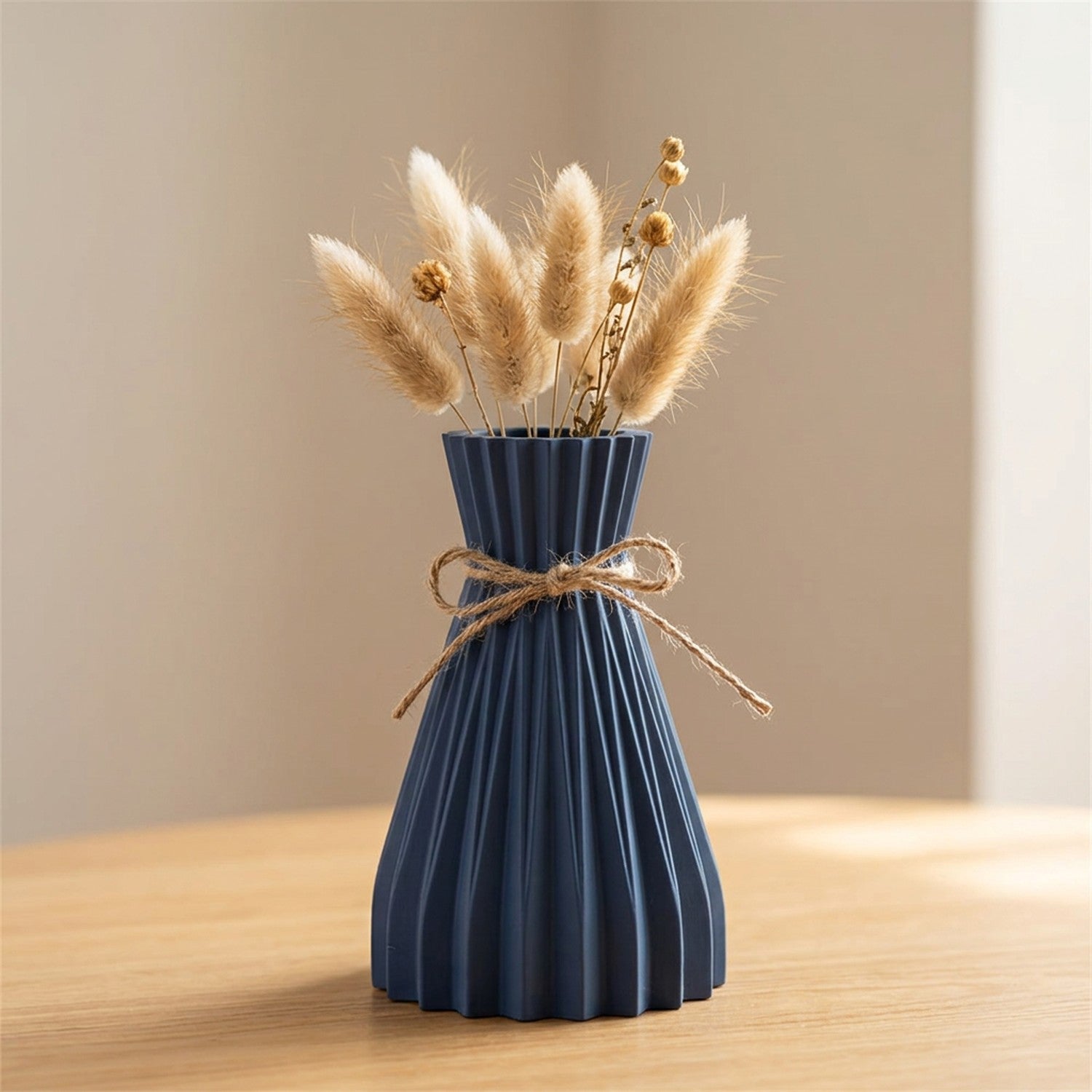 Vase origami plissé bleu foncé en plastique avec un nœud en jute et des fleurs séchées