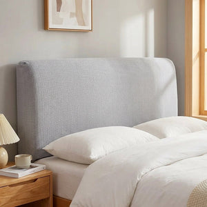 Housse de tête de lit en maille tricotée gris clair installée sur un lit dans une chambre lumineuse