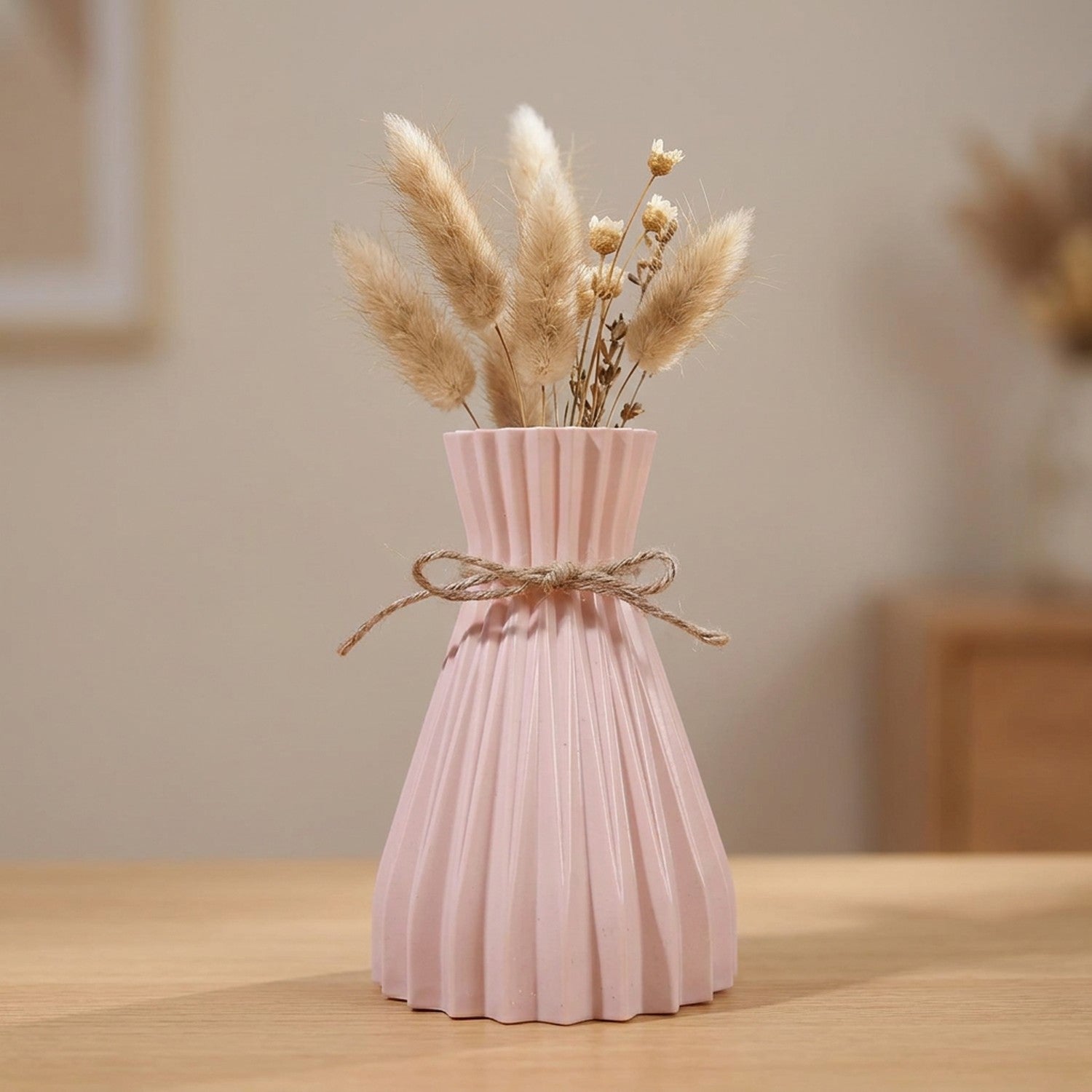 Vase origami plissé rose en plastique avec un nœud en jute et des fleurs séchées