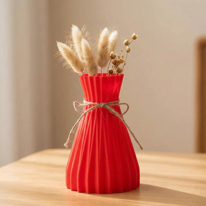 Vase origami plissé rouge en plastique avec un nœud en jute et des fleurs séchées
