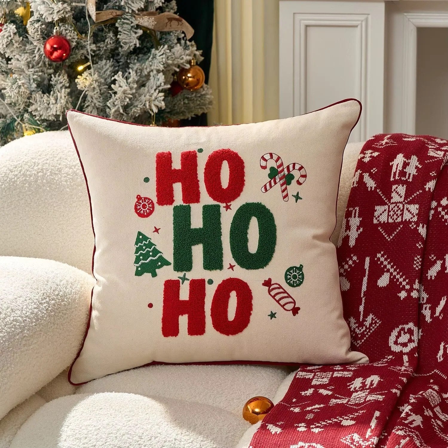 Housse de coussin crème brodée HO HO HO colorée sur canapé cosy