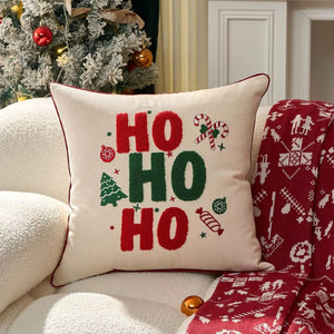Housse de coussin crème brodée HO HO HO colorée sur canapé cosy