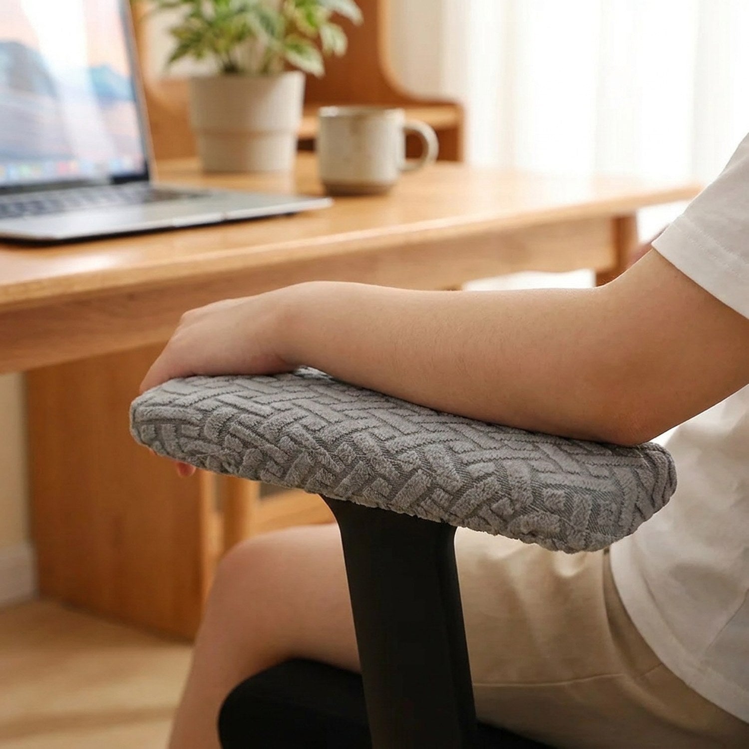 Bras posé sur l'accoudoir d'une chaise de bureau habillé d'une housse jacquard grise