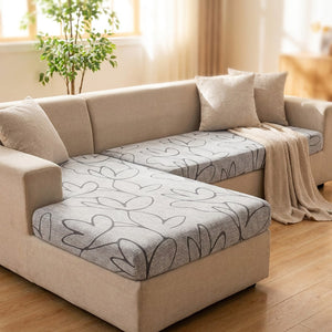Housse de coussin d'assise extensible au motif feuillage gris posée sur les assises d'un canapé d'angle lumineux