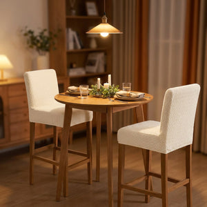 Petite table à manger entourée de deux chaises hautes habillées de housses beiges en soirée