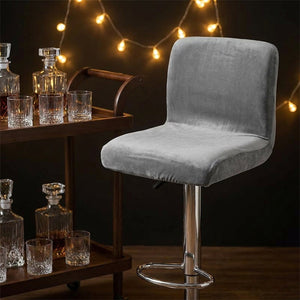 Chaise de bar habillée de velours gris près d un chariot à boissons