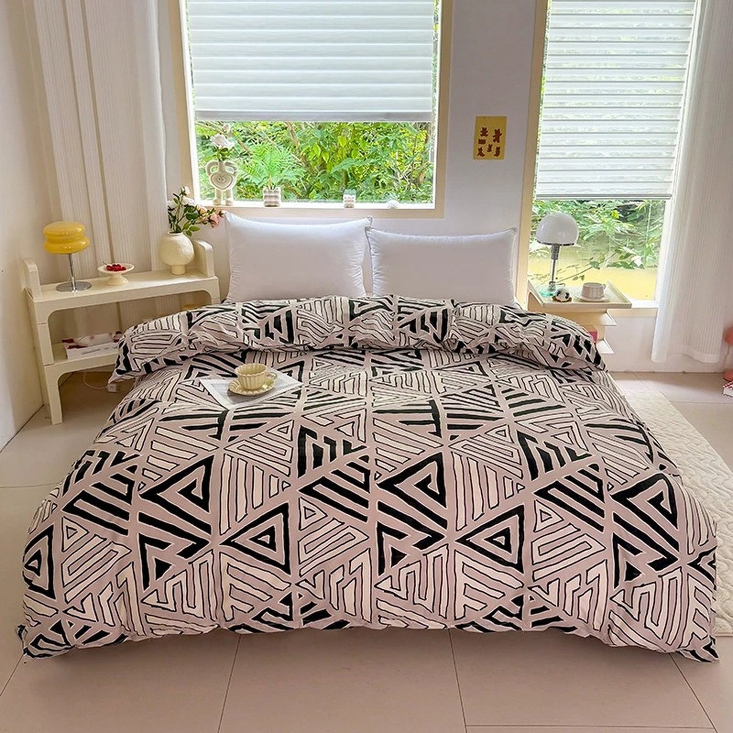 Housse de couette beige motif géométrique posée sur un lit dans une chambre lumineuse avec rideaux blancs