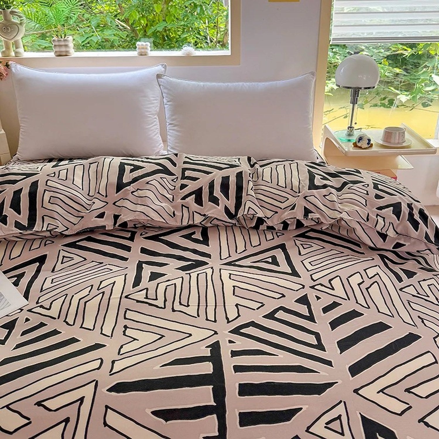 Housse de couette et taies assorties à motif géométrique posées contre des oreillers blancs