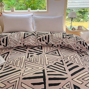 Housse de couette et taies assorties à motif géométrique posées contre des oreillers blancs