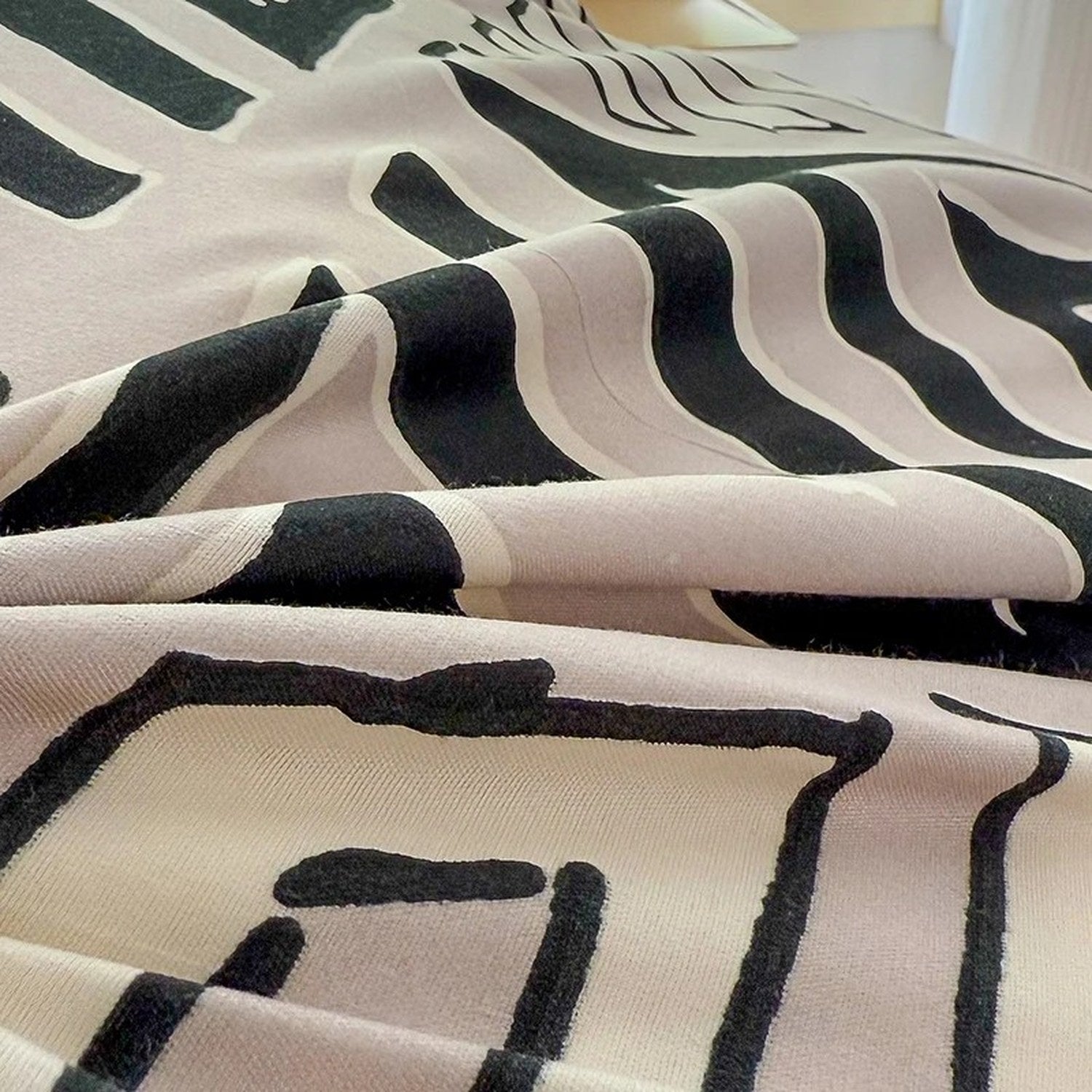 Détail du tissu plissé de la housse de couette au motif géométrique noir sur fond beige