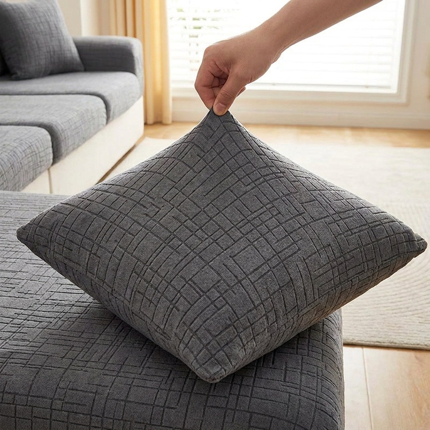 Main tirant sur la housse de coussin grise pour montrer son élasticité