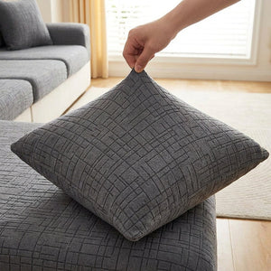 Main tirant sur la housse de coussin grise pour montrer son élasticité