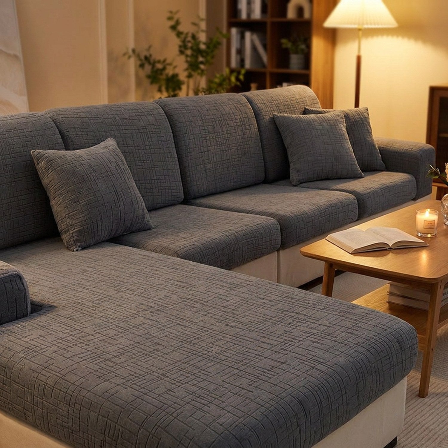 Canapé d'angle entièrement habillé de housses de coussin grises en soirée