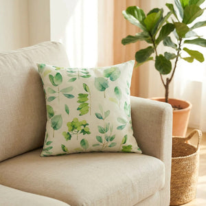 Housse de coussin à feuillage vert posée sur un canapé en lin dans un salon lumineux