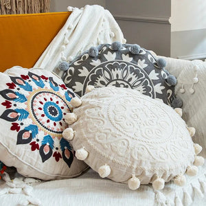 Housses de coussin rondes bohèmes empilées sur un canapé avec pompons