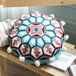 Housse de coussin ronde brodée mandala turquoise et corail sur une étagère en bois