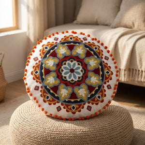 Housse de coussin ronde bohème posée sur un pouf en fibre naturelle dans un coin salon