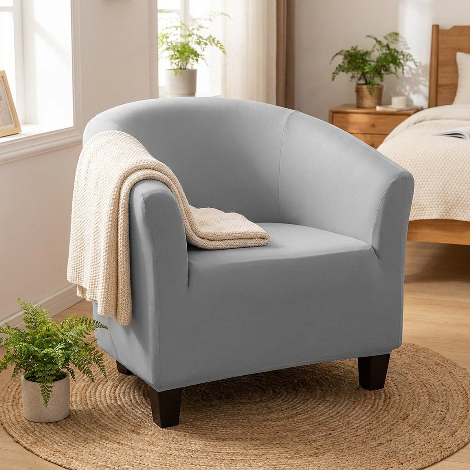 Fauteuil crapaud avec housse grise dans une chambre cosy avec un plaid