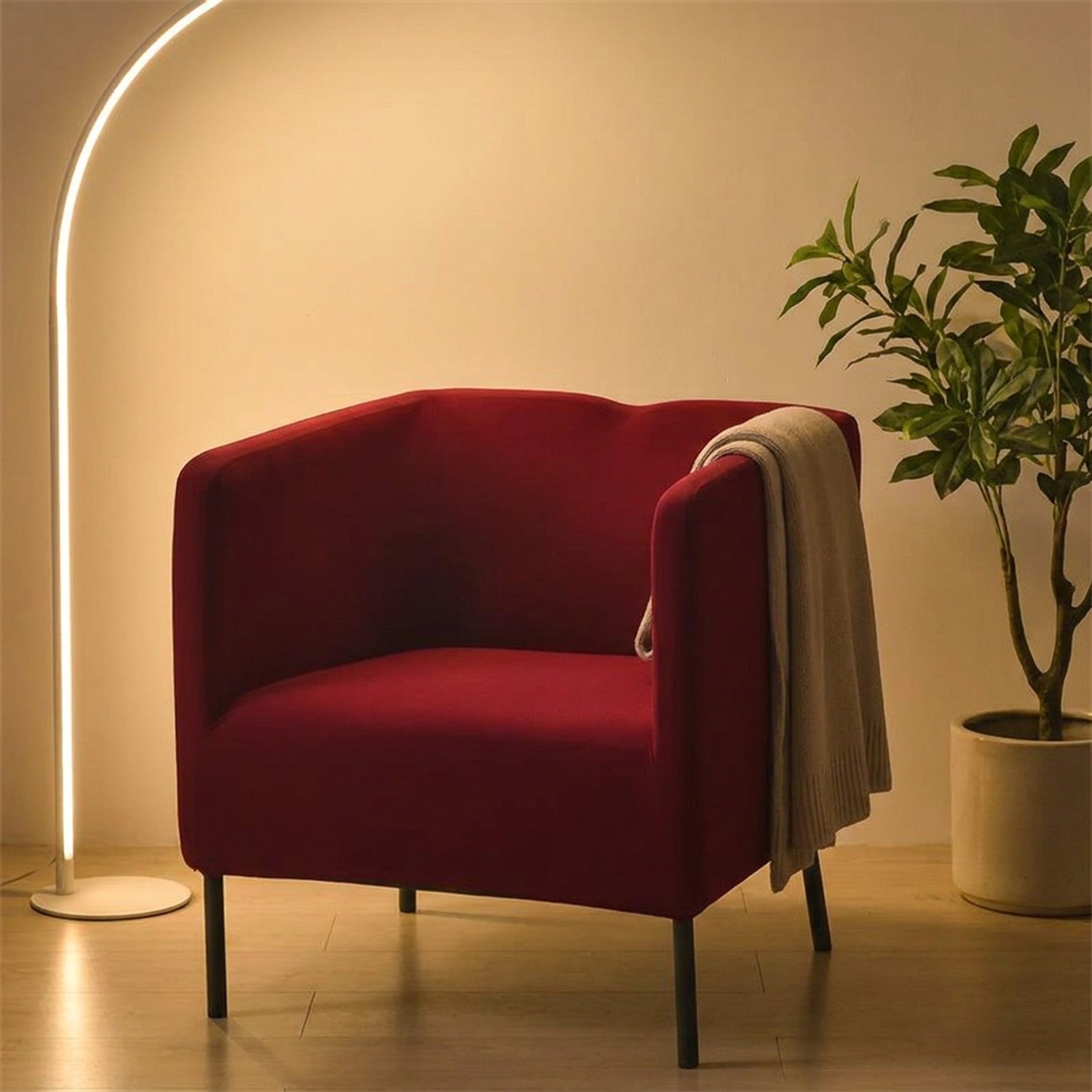 Housse de fauteuil bordeaux sur un fauteuil dans un coin lecture chaleureux