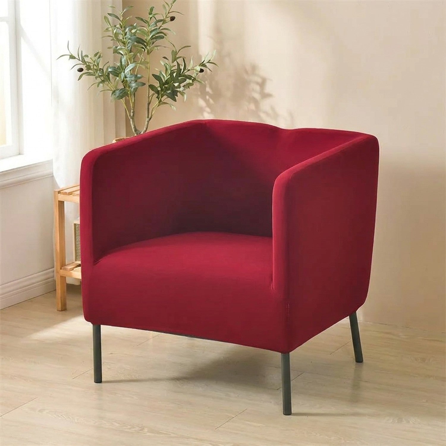 Housse de fauteuil club extensible coloris grenat bordeaux installée dans un salon lumineux