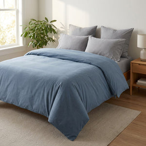 Housse de couette bleue sur un grand lit dans une chambre lumineuse et chaleureuse