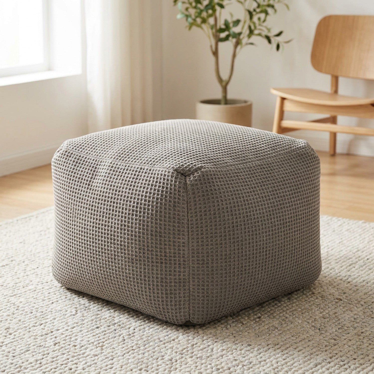 Pouf poire carré en coton gaufré gris posé sur un tapis clair