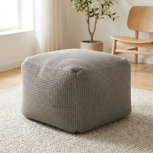 Pouf poire carré en coton gaufré gris posé sur un tapis clair