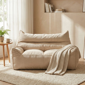Canapé poire beige en tissu gaufré installé dans un coin salon cosy avec plaid